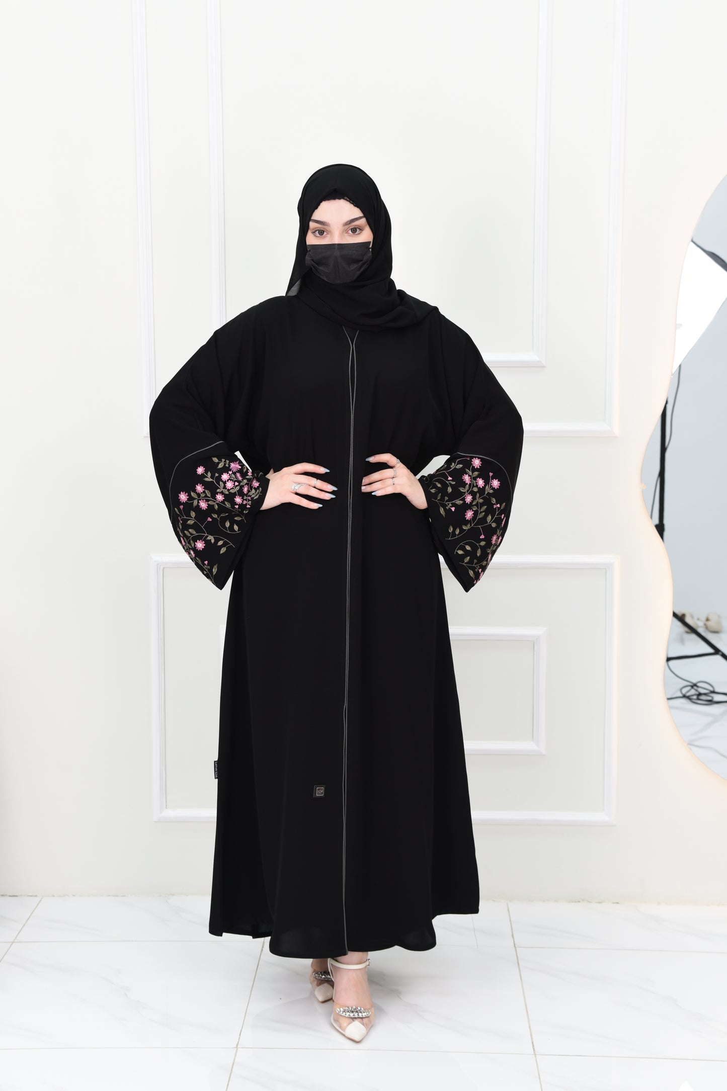 Black abaya adorned with delicate pink embroidery and accented with olive green trim
