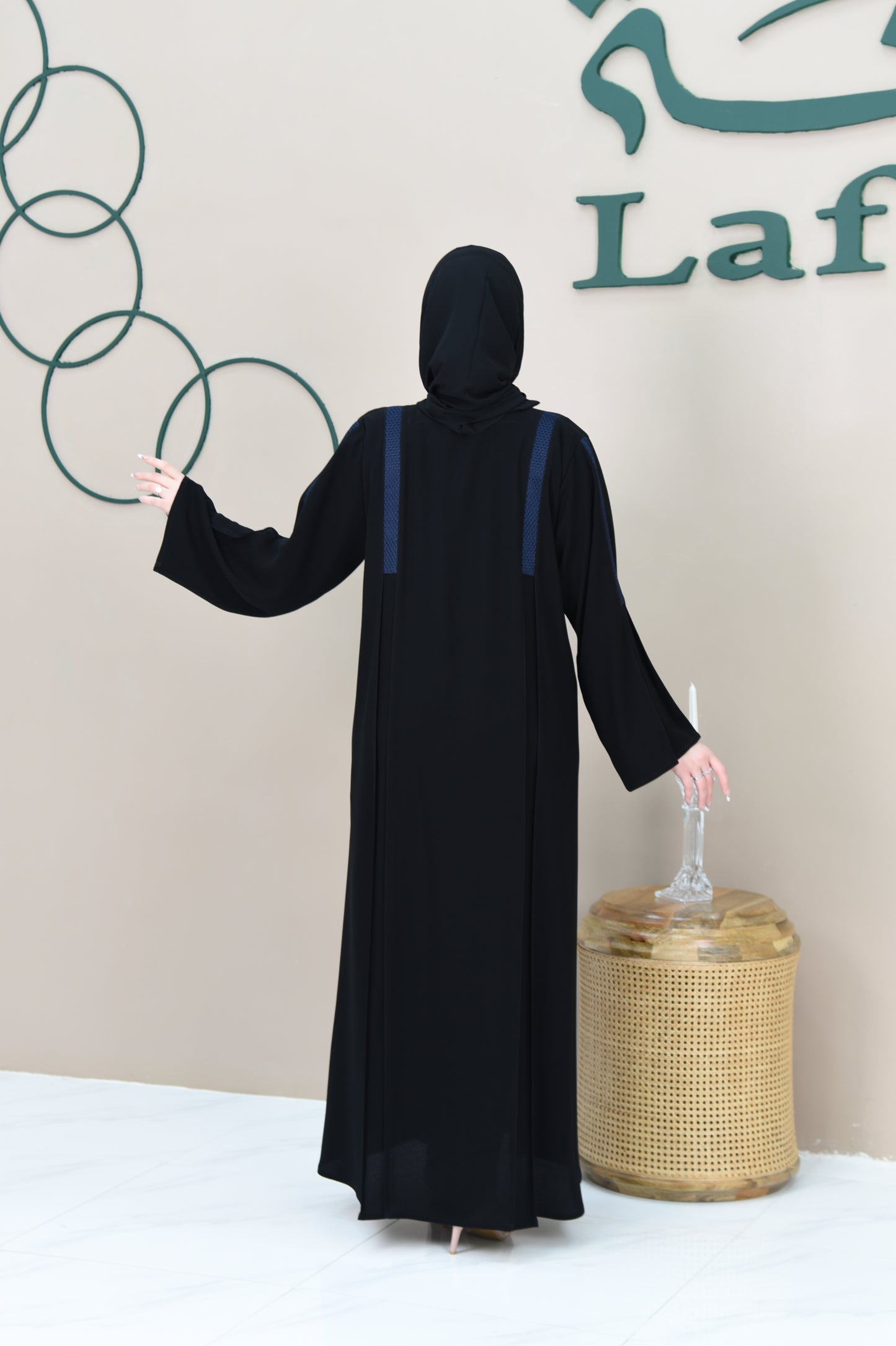 A pleated cloche abaya adorned with navy blue lace trim