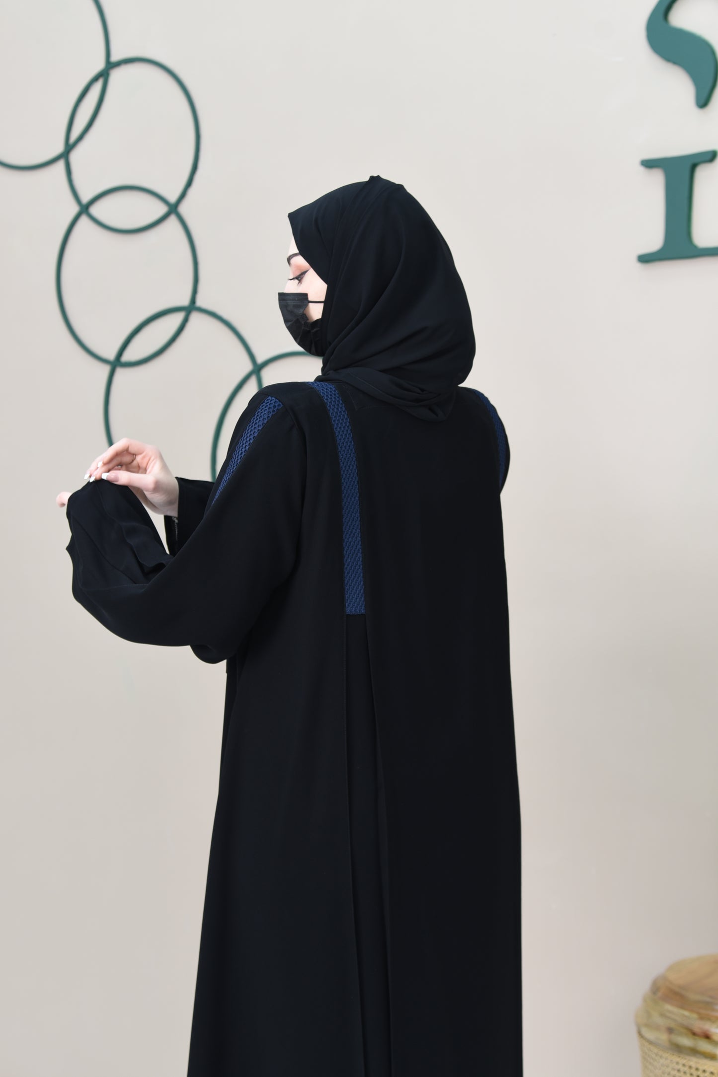 A pleated cloche abaya adorned with navy blue lace trim