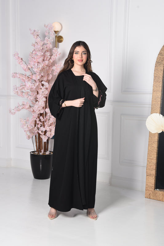 An abaya with pink and gold accents on black crepe fabric
