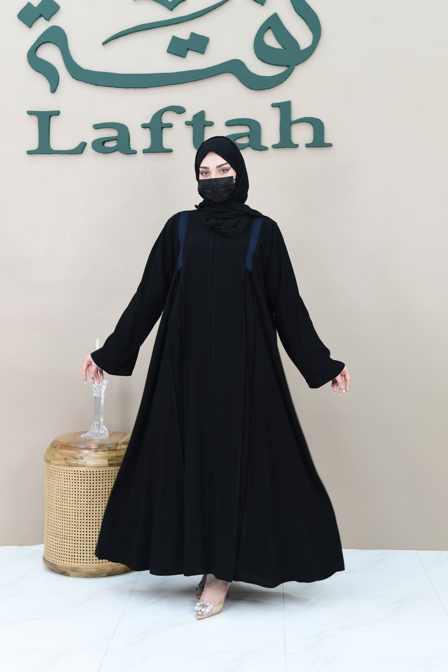 A pleated cloche abaya adorned with navy blue lace trim