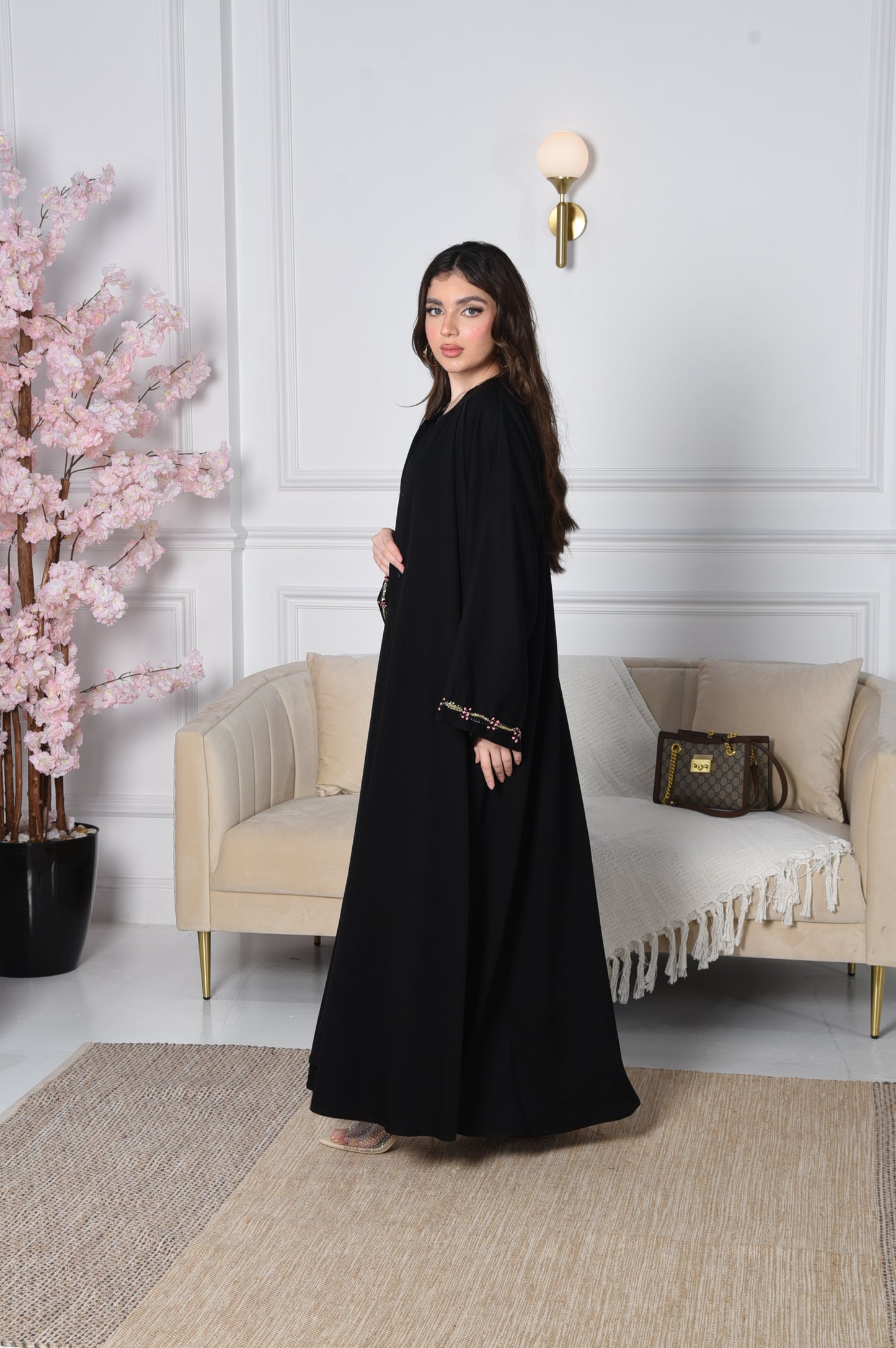 An abaya with pink and gold accents on black crepe fabric