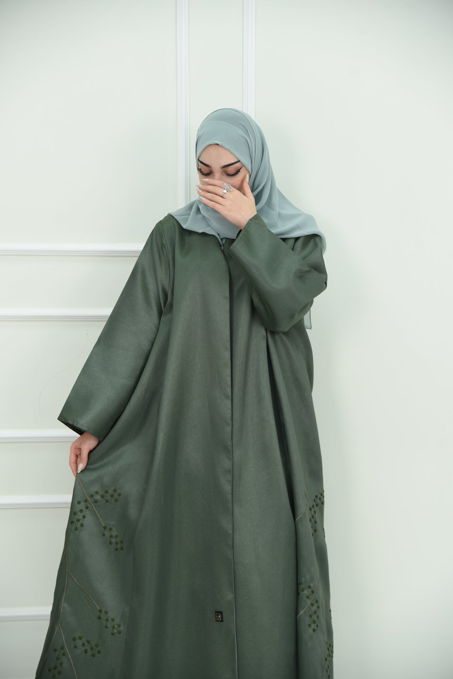 An elegant olive green abaya designed with an exquisite embroidery along the lower hem