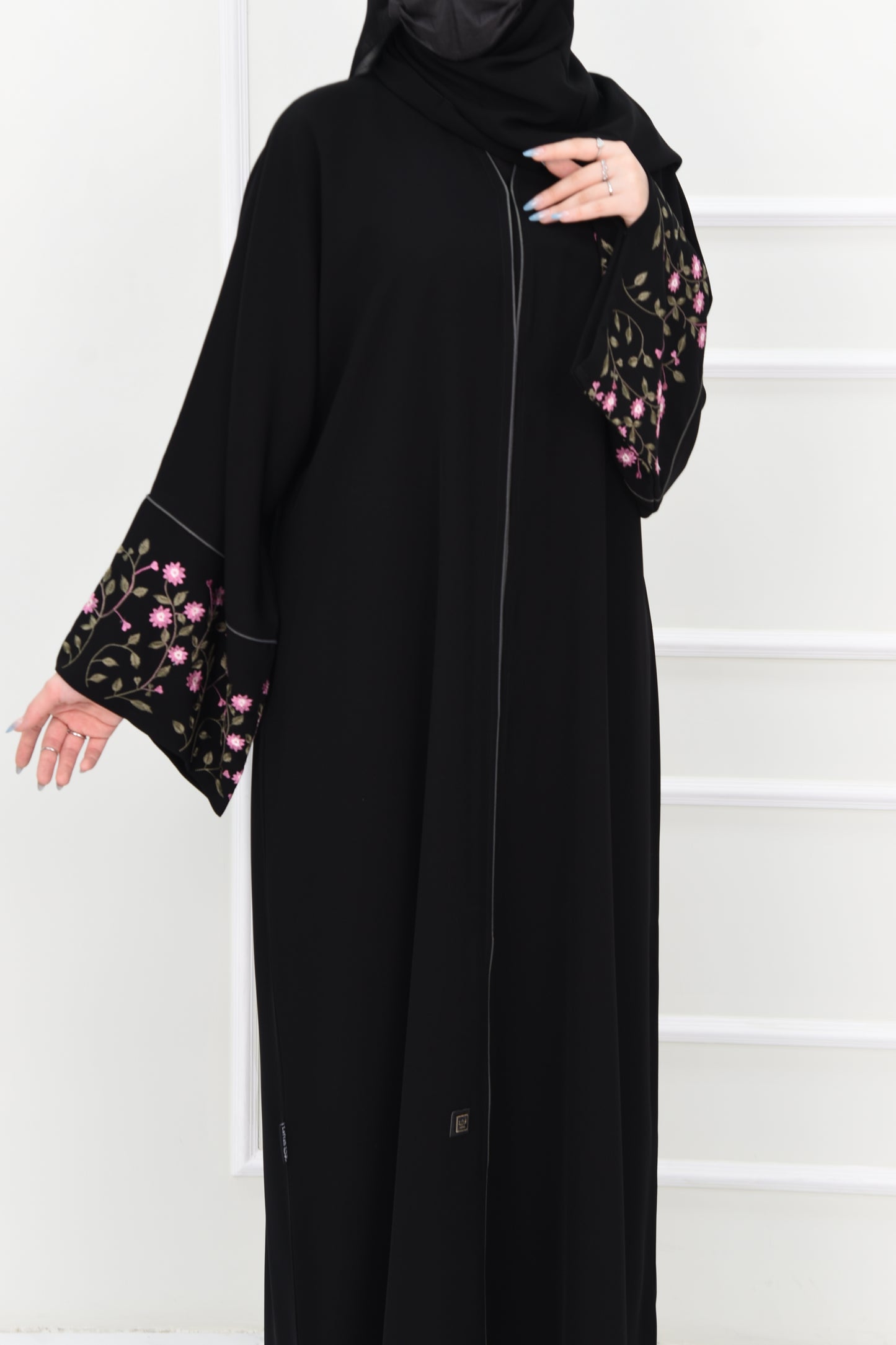 Black abaya adorned with delicate pink embroidery and accented with olive green trim