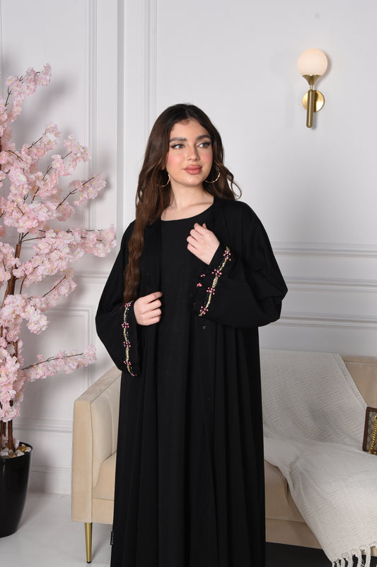 An abaya with pink and gold accents on black crepe fabric